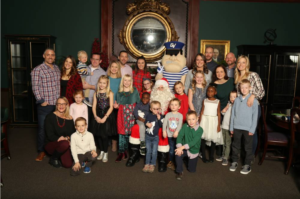 Alumni families posing with Louie and Santa Claus